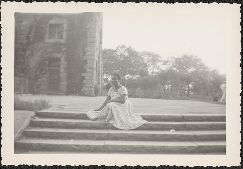 A woman sits on steps wearing a dress