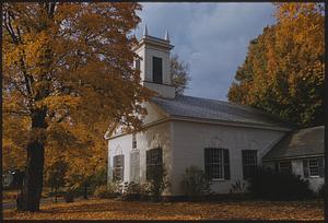 Fall trees and fallen leaves around small white church