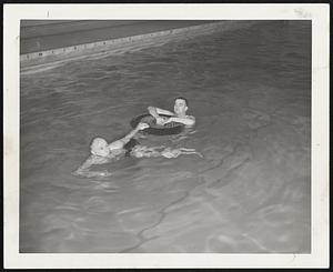 Life Saving is possible for every motorist if he remembers the spare tire in the trunk of his automobile, according to two Newton safety officers. Gil Champagne demonstrates how a non-swimmer can be pulled to safety using a spare tire that will support four men. Safety Officer Charles E. Feeley is the "victim."