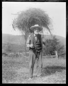 Old farmer with pitch fork full of hay