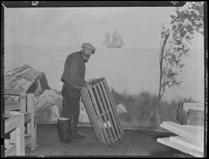 Man with lobster trap posing in front of painted maritime backdrop