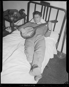 Man playing banjo in bed