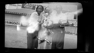 Three women stand holding a ventriloquist dummy