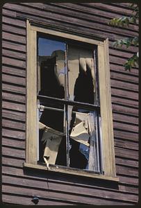 Exterior view of ripped paper or fabric hanging in window, Roxbury, Boston