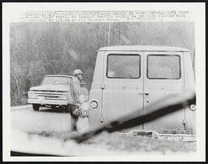 Flagman stands in heavy driving hail storm near here 12/27 trying to unsnarl traffic trying to get into Klamath that was devasted by waters of the Klamath River.