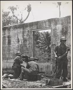 Marines on Guam, expecting a Japanese attack, place heavy machine guns in the windows of a battered house