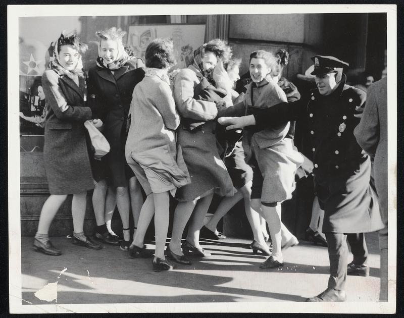 Winter Scene Without Snow at the corner of Boylston and Tremont streets yesterday when cold winds lashed pedestrians, almost knocking them down. The girls seem to be keeping their feet pretty well with a policeman on hand in case of emergency.