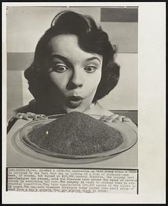 What a Dish-The expression on this young woman's face is inspired by the fact that she is looking at a dish of diamonds--man made, of course, but valued at $30,000. General Electric, the company that manufactures the stones, said the diamonds have proved the equal of natural stones in everything but size. The company is ready to produce them in substantial quantities. They have manufactured 100,000 carats of the stones in 2 1/2 years. The man-made diamonds displayed today looked like small piles of sand from a boy's pockets. They are grayish black in color.