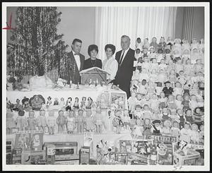 Woman Employes of the Federal Reserve Bank of Boston dressed a total of 420 dolls, many of them shown here, for distribution to youngsters in orphanages and hospitals. On committee, from left: George Mullen, Virginia Joyce, Rosemarie Olivolo and Frederick Donahue.