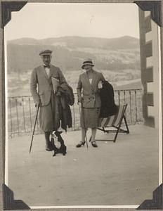 A Boston terrier sits in front of an unidentified man and woman