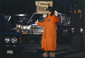Woman police officer directs traffic in orange raincoat, Boston