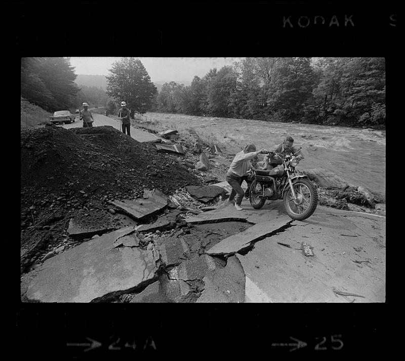 Motorcyclists negotiate washed-out road from Black River flooding, Springfield, Vermont