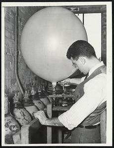 Winds Aloft are investigated by means of huge inflated balloons, such as this one, being blown up by Charles Brister of Cambridge of the staff of Boston's new weather forecasting center.