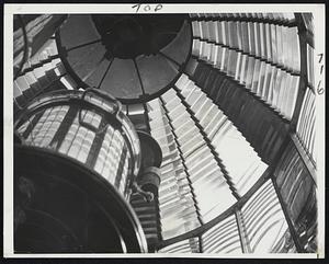 Inside a Lighthouse-The massive Fresnel lens of the Gay Head Lighthouse on Martha's Vineyard which contains 1003 prisms may be brought to Boston's new Museum of Science, since Coast Guard plans to electrify the gasoline light would make the lens obsolete. Rotation of prisms, visible at right, account for the beacon's distinctive three white and one red flash.