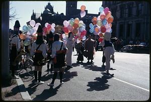People holding balloons, some wearing costumes, Old South Church in background, Boston Columbus Day Parade 1973