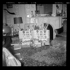 A display of opened Christmas presents in front of a fireplace