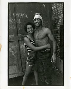 A woman and a shirtless man embracing