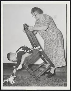 Grandma Turns Inventor. Mrs. C.R. Shaw, who is 64 and a grandmother, became an inventor because she was tired of picking her two-year-old grandson up off the floor after his frequent falls off chair. Mrs. Shaw fashioned and received a patent this week on the safety strap shown being worn by Gerald Mader, whose toppling led to his grandmother's brainchild. They demonstrate how the child can reach for objects without falling and how he can be moved along with the chair.