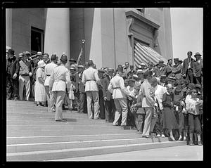 A crowd of people being held back by men in uniform