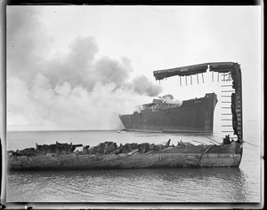 Burning wooden ship 'Wakanna' through ruin of another. Scrapped, Boston Harbor.