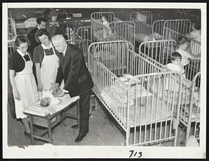Nursery in flood time was Classical High School in Springfield, which houses scores of children as can be seen from these tightly packed rows of cribs that were rushed into service when families were driven from their homes. A tiny refugee, ill, perhaps from a sudden change of home, is shown being cared for by a doctor. This picture is the first from Springfield to reach any outside city.