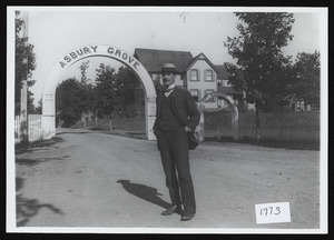 Watchman standing outside Asbury Grove, So. Hamilton, Mass., entrance gates, c. 1907