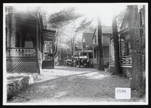 View down an avenue of cottages showing two automobiles, Asbury Grove, So. Hamilton, Mass