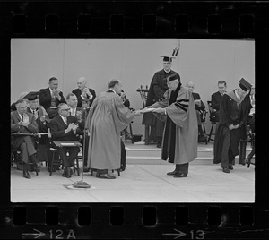 UN Envoy Adlai Stevenson accepts his honorary degree at Harvard Commencement. Seated are Galo Plaza, (left), Ecuador (seated left) and Romulo Betancourt of Venezuela