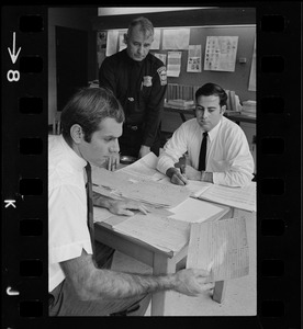Three men examining Boston Police arrest records