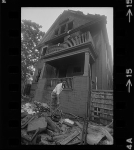 Luis Carvalno holding burned tricycle outside of ruins of house fire on Gayland Street, Roxbury, in which seven of his relatives died