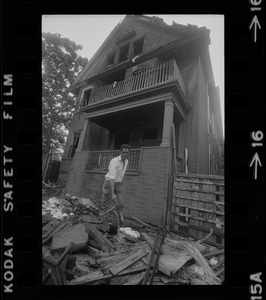 Luis Carvalno holding burned tricycle outside of ruins of house fire on Gayland Street, Roxbury, in which seven of his relatives died