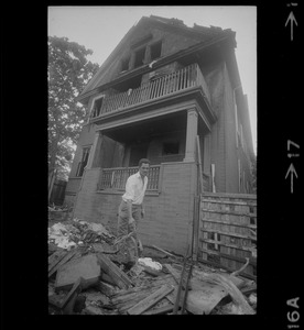 Luis Carvalno holding burned tricycle outside of ruins of house fire on Gayland Street, Roxbury, in which seven of his relatives died