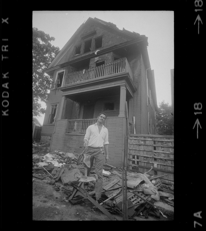 Luis Carvalno holding burned tricycle outside of ruins of house fire on Gayland Street, Roxbury, in which seven of his relatives died