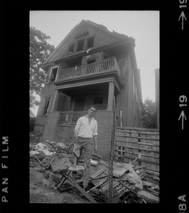 Luis Carvalno holding burned tricycle outside of ruins of house fire on Gayland Street, Roxbury, in which seven of his relatives died