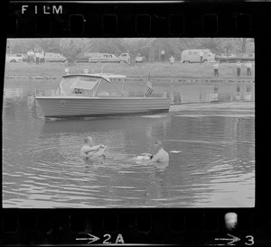 Two men retrieving papers from water