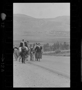 Group of people with donkeys walking along desert road, Israel