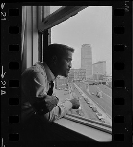 Sammy Davis, Jr., the star of Broadway hit musical "Golden Boy," views Hub skyline from his suite at Hotel Somerset
