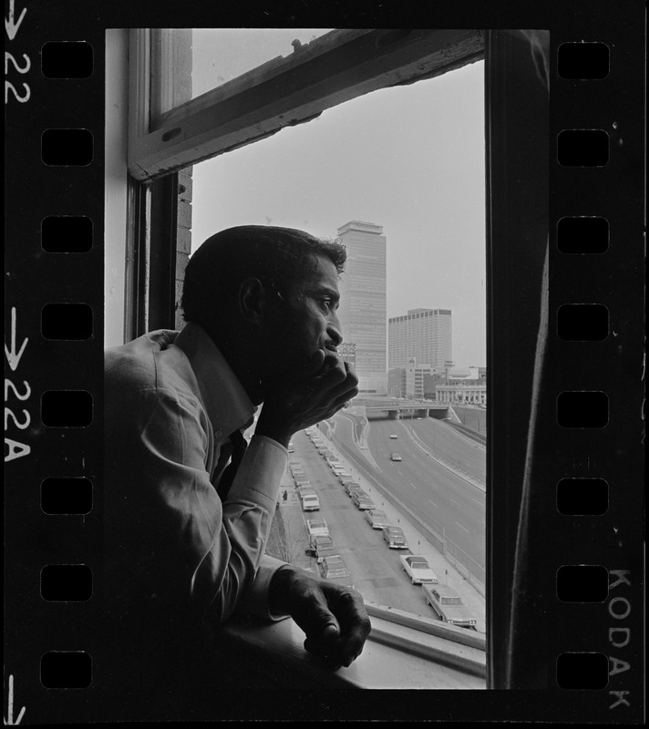 Sammy Davis, Jr., the star of Broadway hit musical "Golden Boy," views Hub skyline from his suite at Hotel Somerset