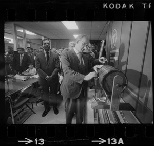 MBTA chair Robert C. Wood drawing name of job applicant from raffle drum as George Coblyn watches