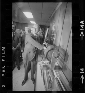 MBTA chair Robert C. Wood drawing name of job applicant from raffle drum as George Coblyn and William J. Fitzsimmons watch