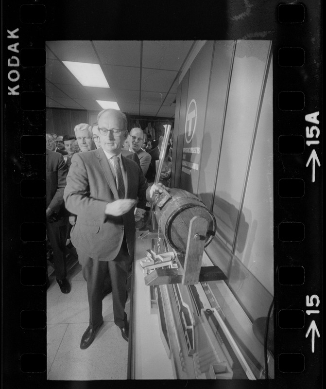 MBTA chair Robert C. Wood drawing name of job applicant from raffle drum as William J. Fitzsimmons watches