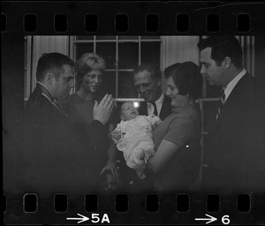 Two-month-old Michael Warner, son of Boston Park Commissioner John Warner (right) is the center of attention as he is baptized by the Rev. Thomas Fleming of St. Patrick's Church, Roxbury. Among those attending the christening, held at Mayor Kevin White's Back Bay home, was the baby's mother, 2nd left, Mayor White, the child's godmother, Mrs. Mary McDonough, wife of city councilor Pat McDonough, and the proud father