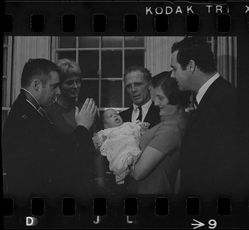 Two-month-old Michael Warner, son of Boston Park Commissioner John Warner (right) is the center of attention as he is baptized by the Rev. Thomas Fleming of St. Patrick's Church, Roxbury. Among those attending the christening, held at Mayor Kevin White's Back Bay home, was the baby's mother, 2nd left, Mayor White, the child's godmother, Mrs. Mary McDonough, wife of city councilor Pat McDonough, and the proud father