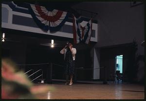 Woman holding camera on stage with bunting