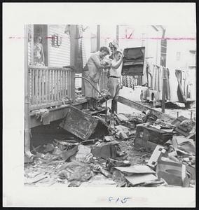 Householder’s Dilemma-The plight of many residents of Woonsocket, R. I., is typified by Mr. and Mrs. Robert Brouillard, trying to salvage as much as possible from their home. The tremendous cleanup task went on yesterday in the area hard hit by flood waters.