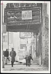 Two Newark children, perhaps not even born when a riot swept this block in 1967, skip homeward over battered sidewalks and past ravaged buildings on Springfield avenue. Half the shops are empty.