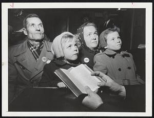 Deep In Thought – Kusma Kandaurow, 61, and his wife, Sofie, 41, and their children, Hanna, 9, and Sonja, 5, listen intently as a clergyman reads Scripture following their arrival in New York City. They arrived with other refugees aboard the Navy Transport General Langfitt.