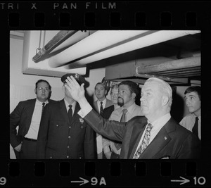 Unidentified men, including police, examining ceiling pipes