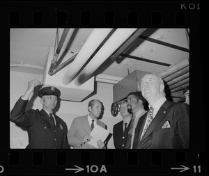 Unidentified men, including police, examining ceiling pipes