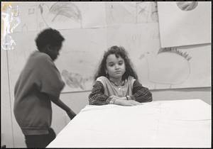 A young girl standing in front of art work